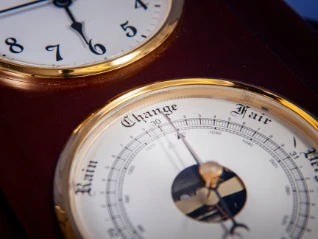 Close-up: Vintage wood/brass weather station shows a barometer face with 'Change, Rain, Fair' below a clock face.