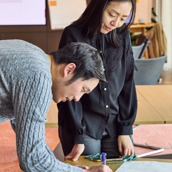 In workshop participating woman and man add their ideas on a sheet