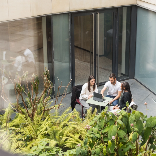 two women and man at a table in a courtyard