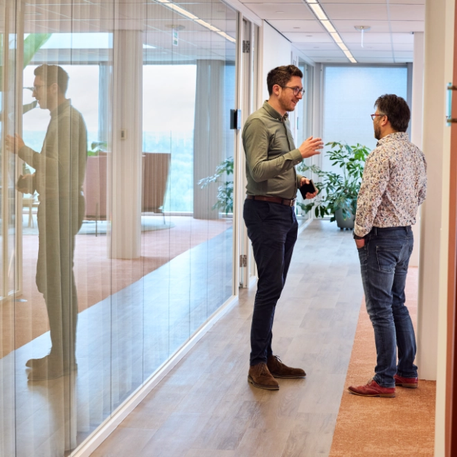 Two colleagues confer briefly in the corridor